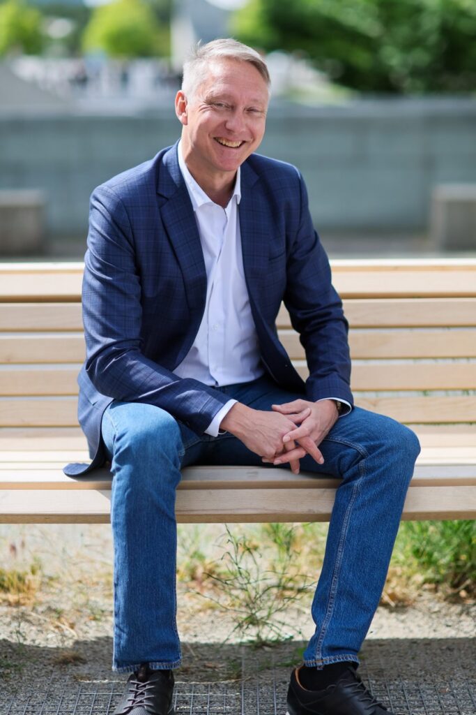 Holger Holland lachend auf einer Holzbank
